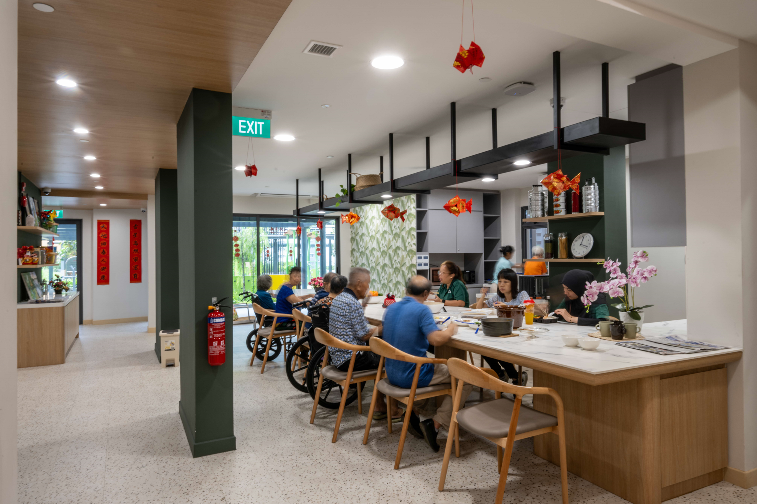 People dining in a brightly lit, accessible assisted living facility with decor.